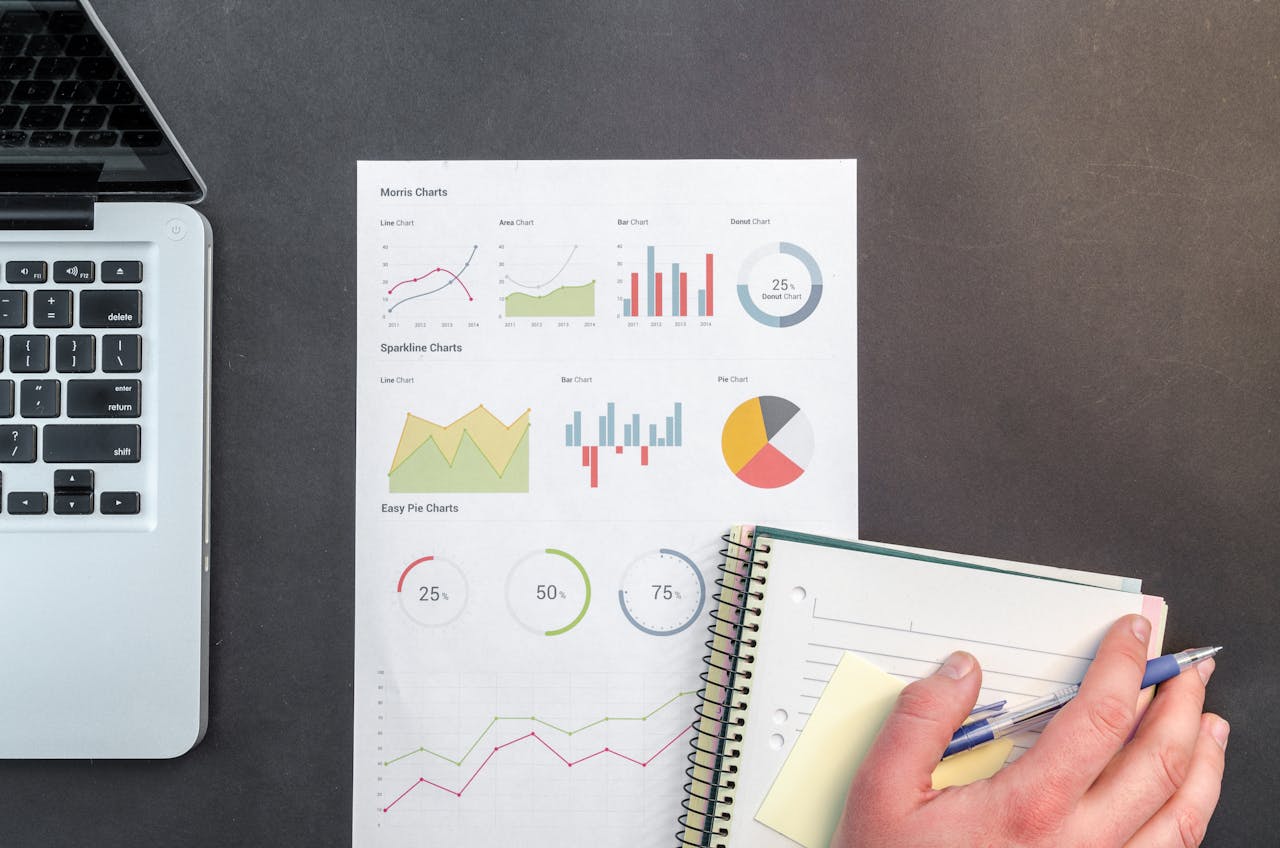 Overhead view of a business desk with charts and a laptop, ideal for data analysis concepts.